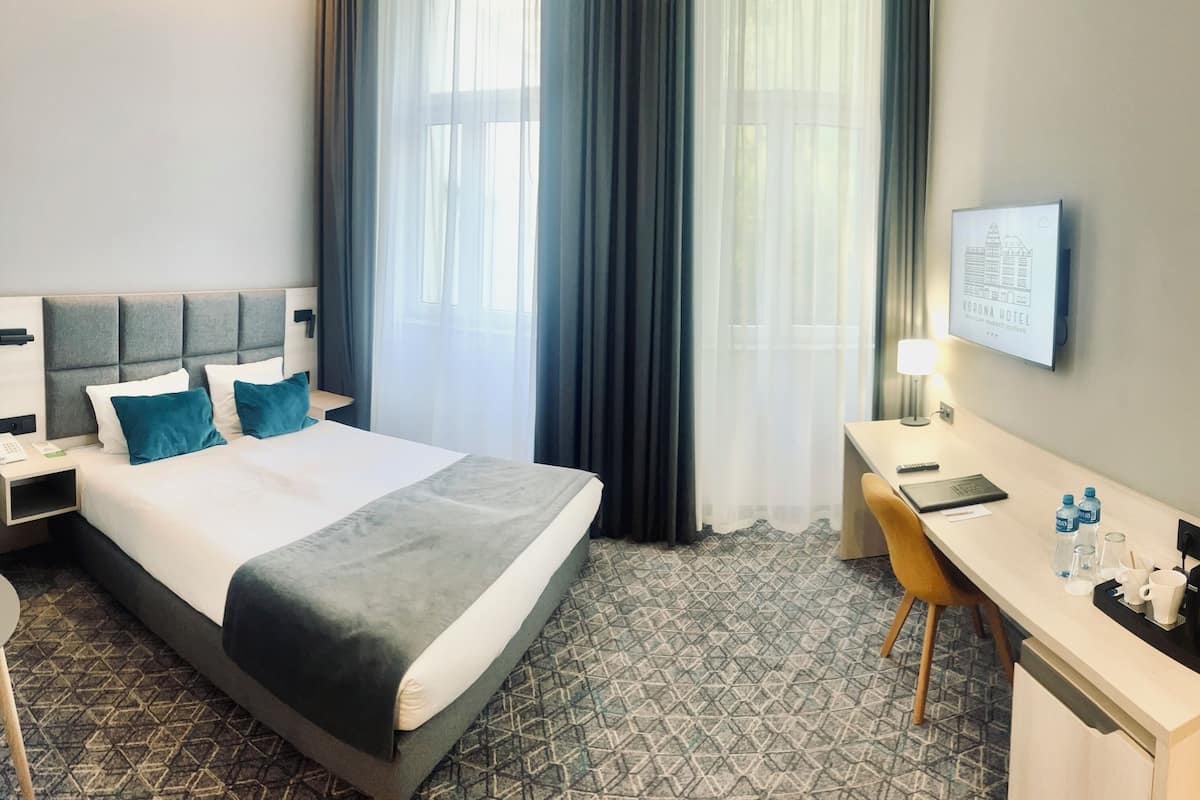 Una habitación de hotel con una cama, un escritorio, una silla y una mesita de noche.