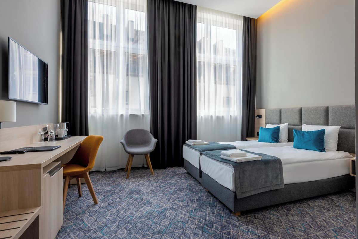 Una habitación de hotel con una cama, un escritorio, una silla y un televisor.