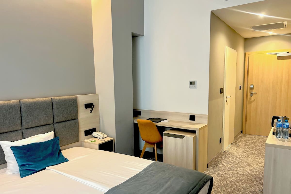 Una habitación de hotel con cama, escritorio, silla y armario.