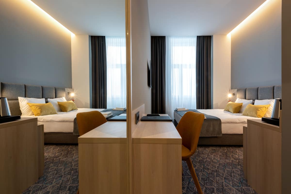 Habitación de hotel con dos camas, un escritorio y una silla.