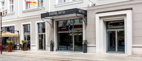 Un hotel con un toldo negro que dice "Corona Hotel".