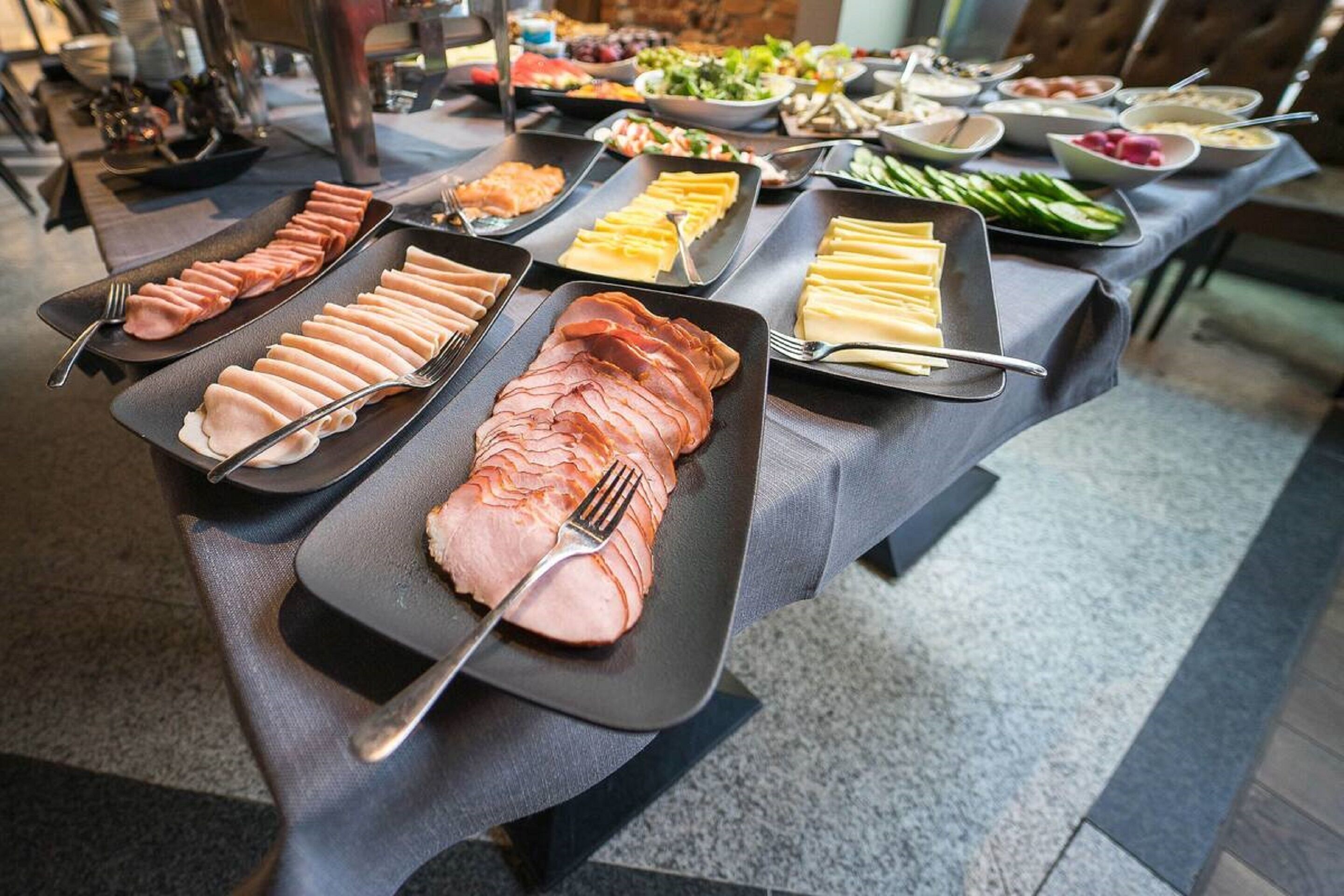 A buffet table with various food items including sliced meats and cheeses.