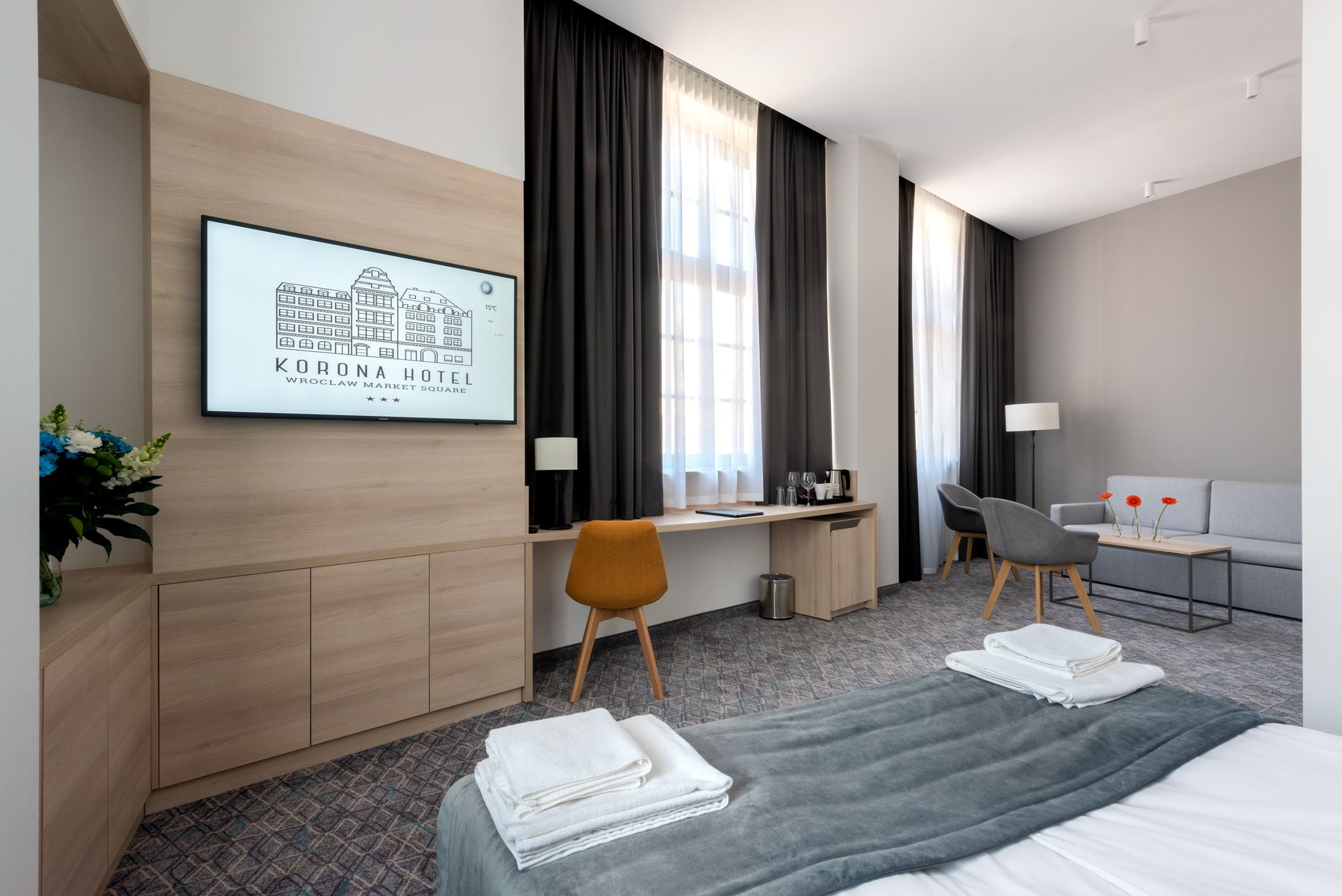 Une chambre d’hôtel avec un lit, un bureau, une chaise, un canapé et un tableau encadré au mur.