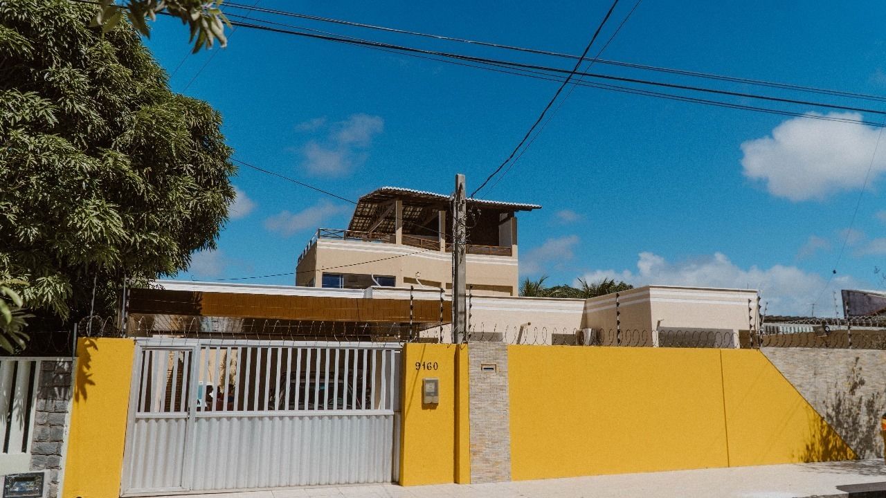 A two-story building with a flat roof and a balcony on the upper floor.