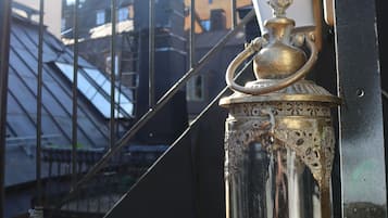 A glass lantern with intricate designs, placed on a tiled surface outdoors.