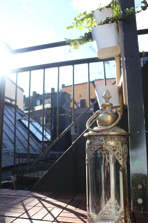 A glass lantern with intricate designs, placed on a tiled surface outdoors. - Divine Living - Apartments (Stockholm)