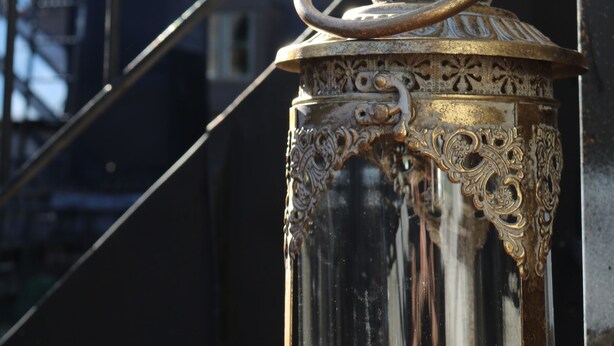 A brass lantern with intricate designs, mounted on a metal pole. - Divine Living - Apartments (Stockholm)