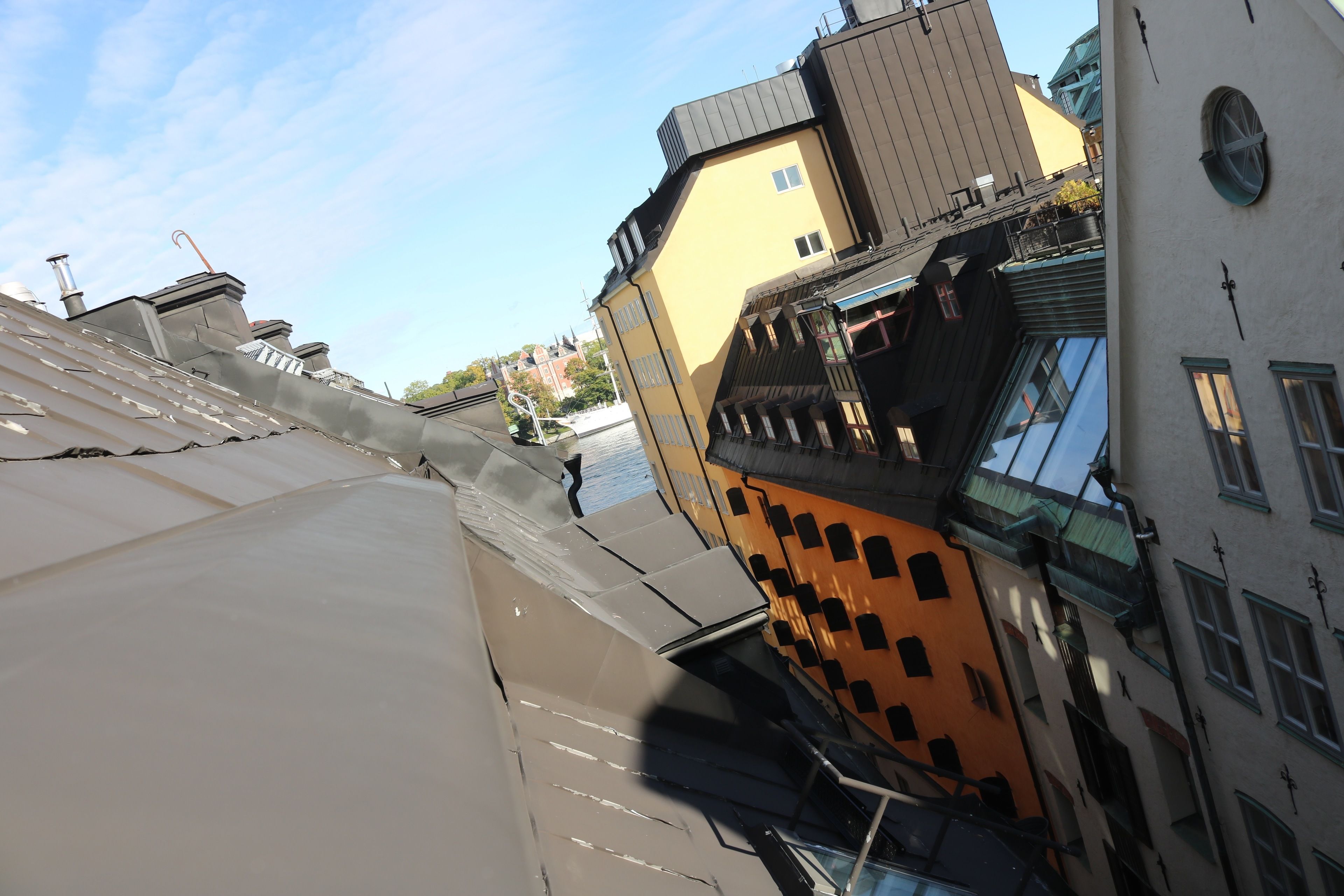 A narrow street with buildings on either side, featuring balconies and a mix of architectural styles.