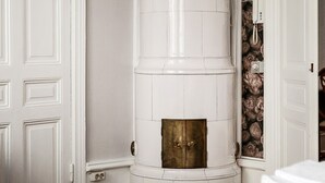 A room with a white wardrobe, a white cylindrical object, and a floral wallpaper section. - Divine Living - Apartments (Stockholm)