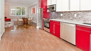 A modern kitchen with red and white cabinetry, a stainless steel refrigerator, a microwave, and an oven. - Home for rent asap now is available to move in (Austin)