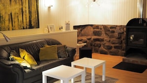 Una sala de estar acogedora con un sofá de cuero negro, una mesa de centro blanca y una chimenea de piedra.