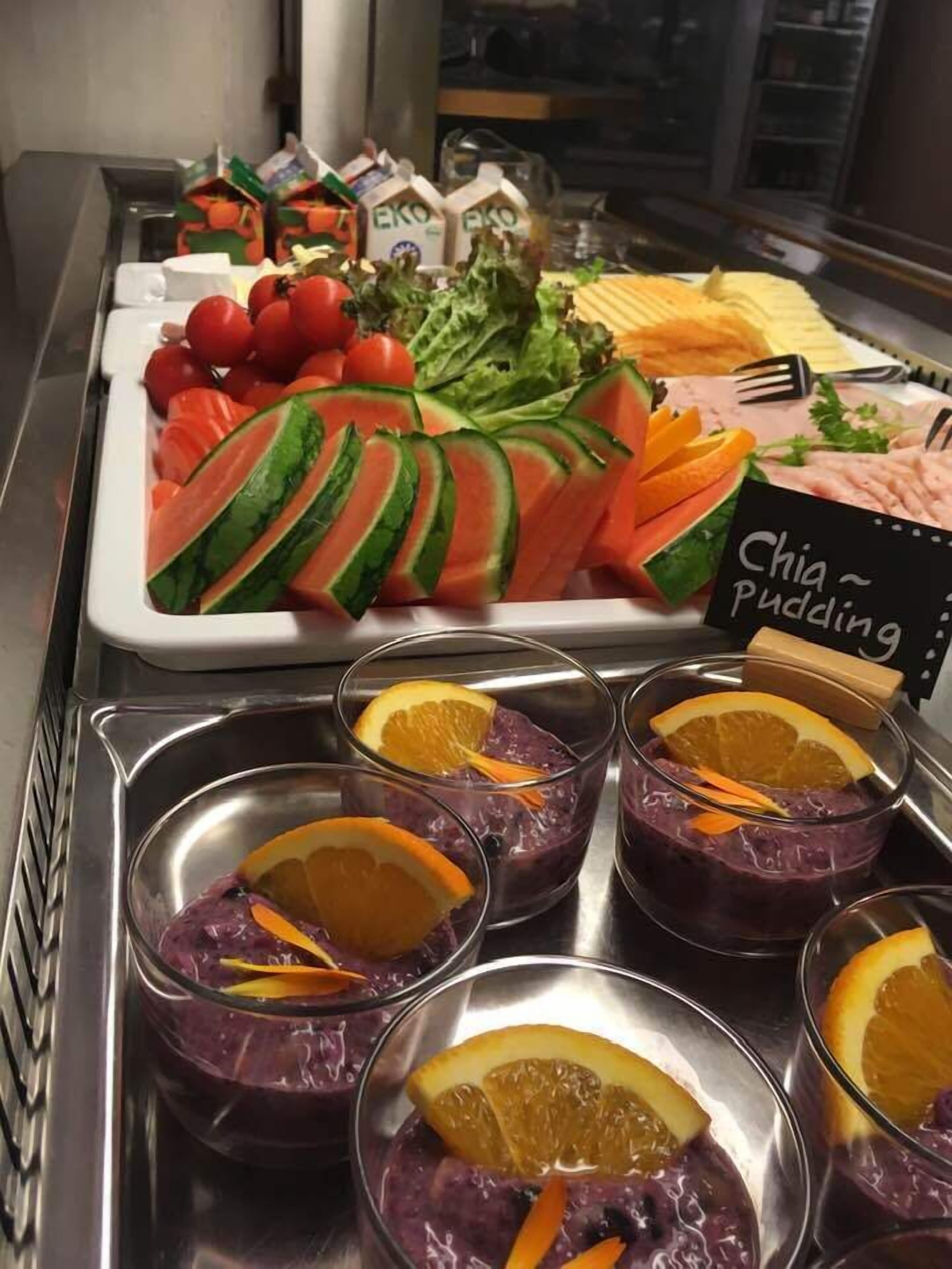 Buffet amb diversos plats, incloent talls de síndria, tomàquets, lletuga i un cartell de pudí de chía.