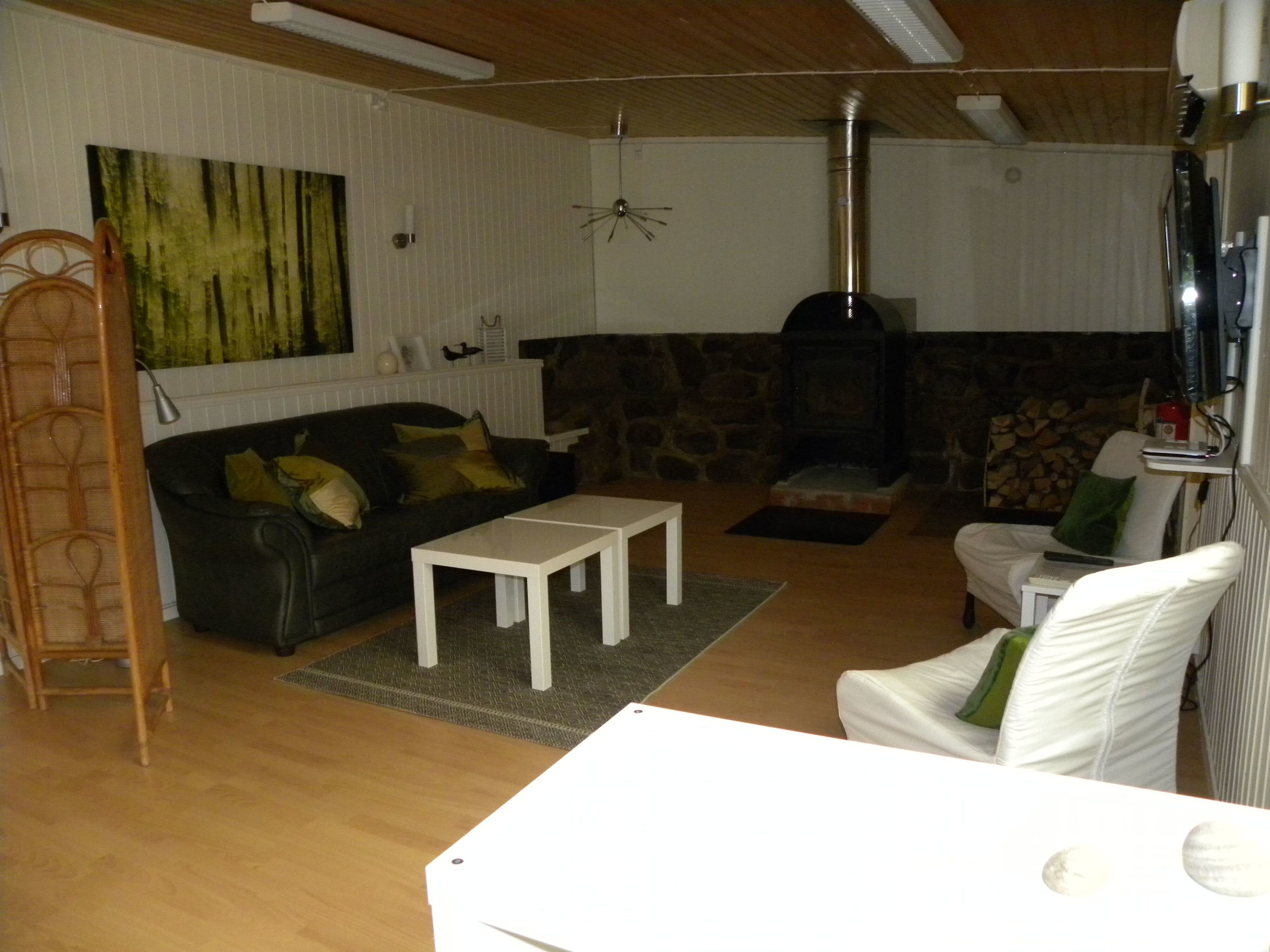 A living room with a stone fireplace, a sofa, a coffee table, and a white armchair.