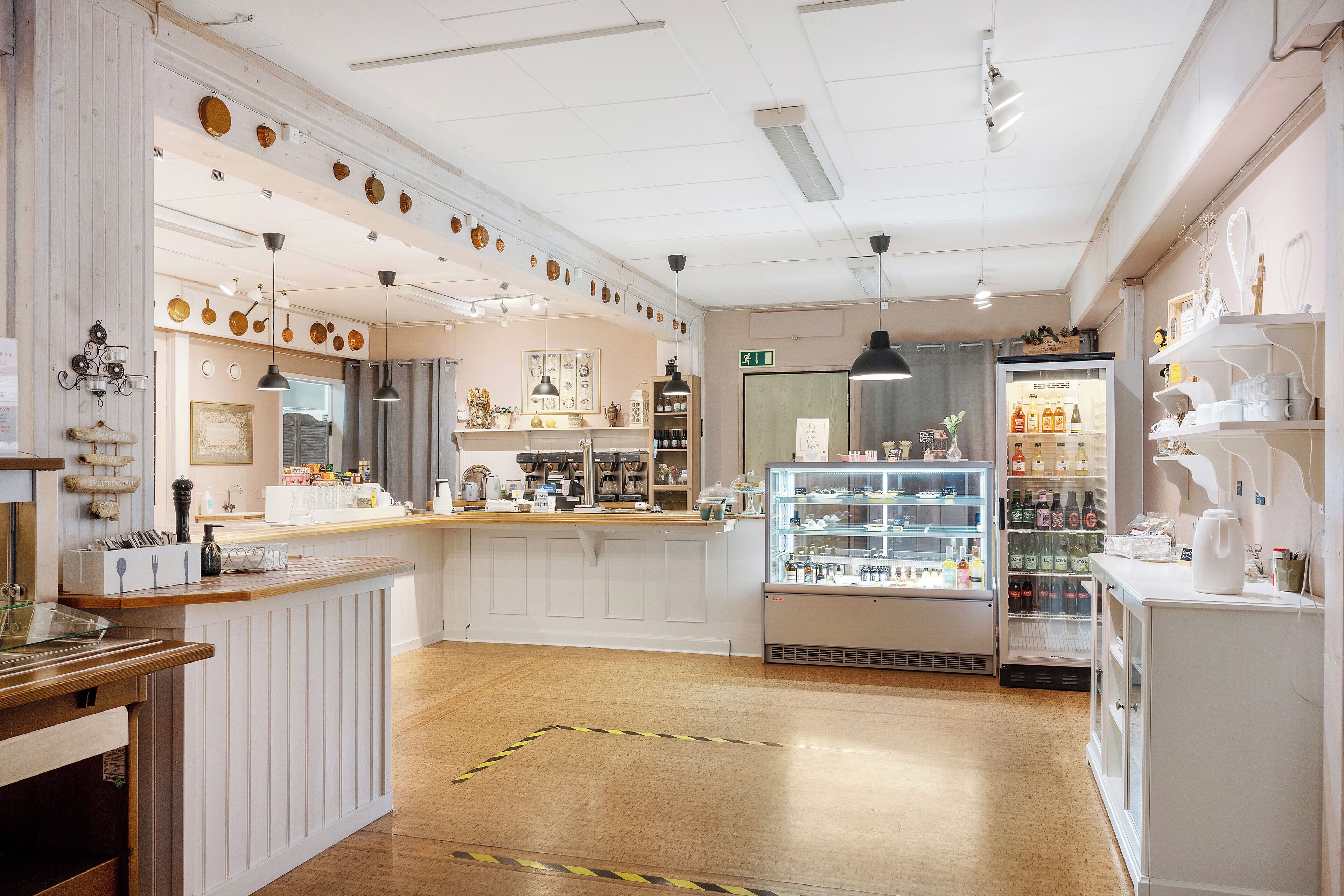 A cafe interior with a counter, display cases, and a refrigerator.