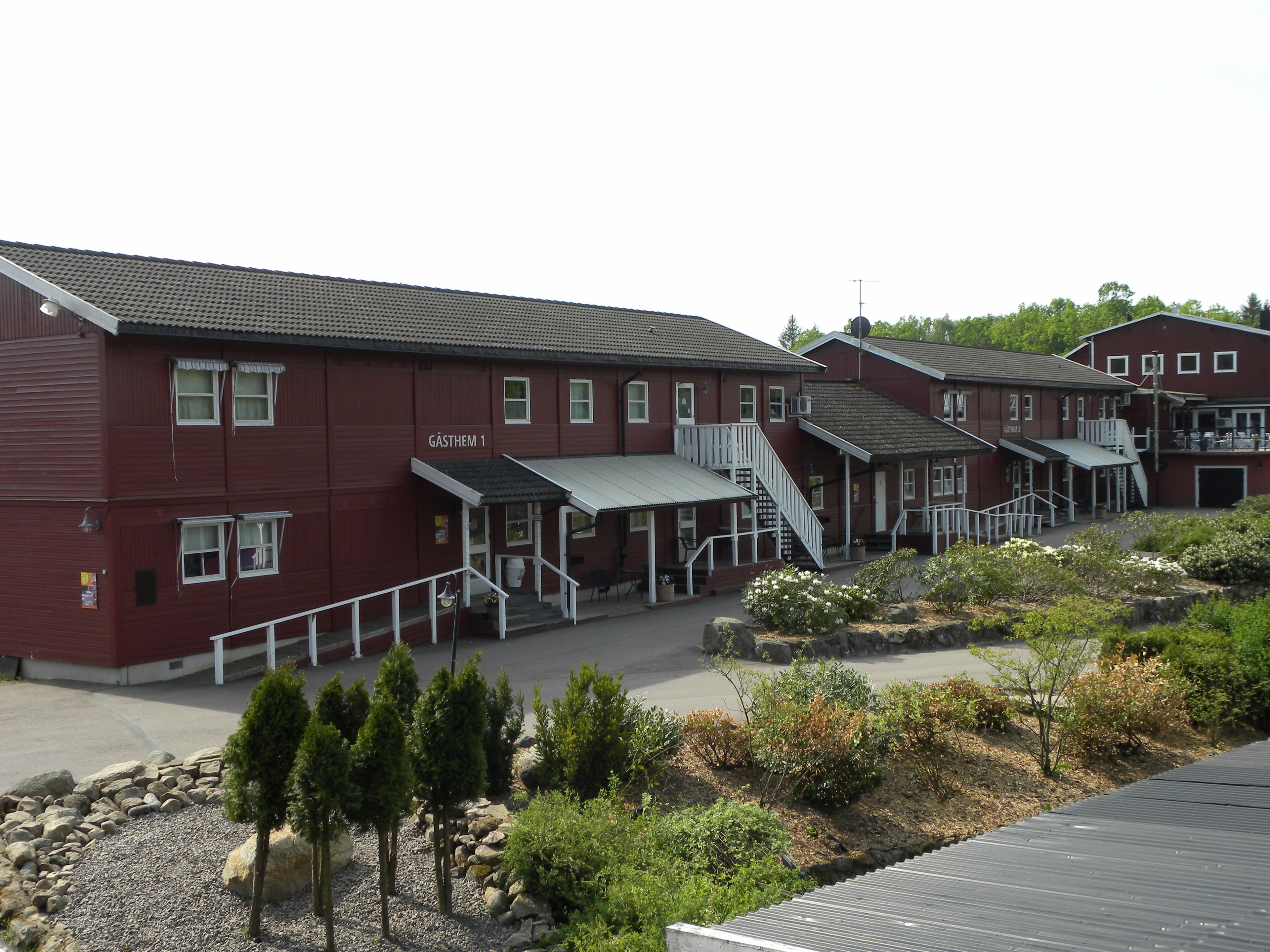 A red building with multiple windows and a staircase leading to a covered entrance.