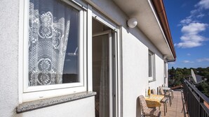 A balcony with outdoor seating, a sliding glass door, and a view of the surrounding area. - Apartments Jakša (Pula)
