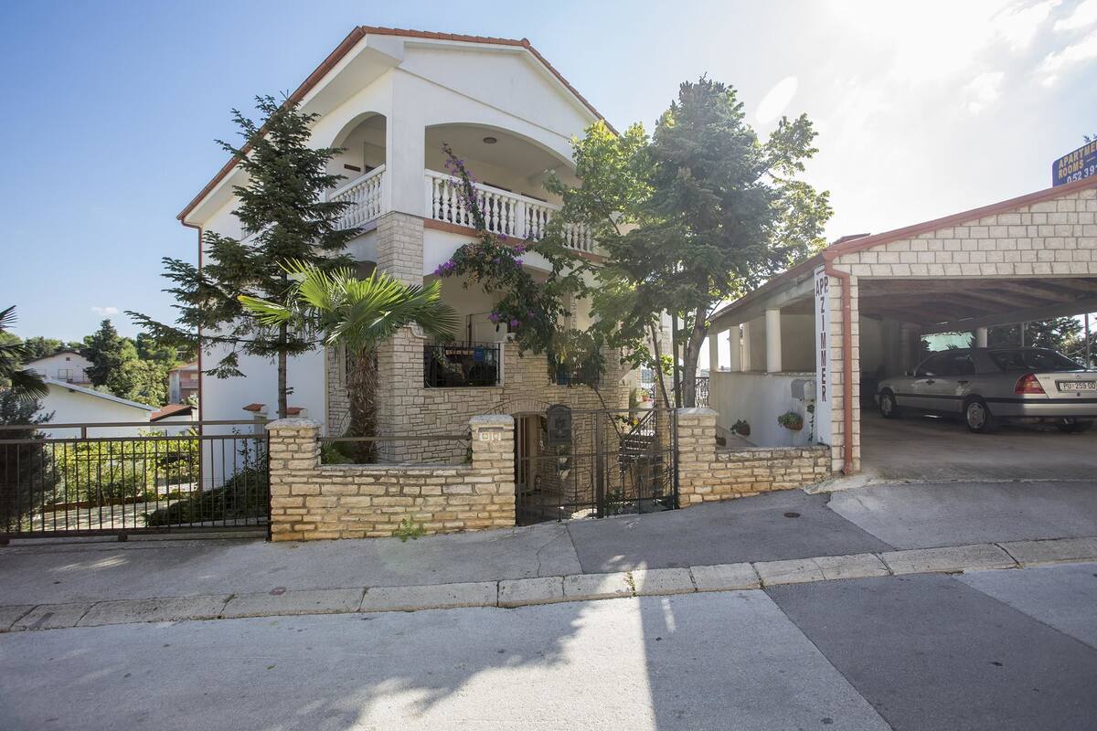 Una casa de dos pisos con balcón, garaje y entrada para vehículos.