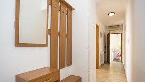 A hallway with a wooden bench, a coat rack, and a door leading to another room. - Apartments Jakša (Pula)