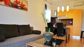 Ett modernt vardagsrum med en grå soffa, ett träbord som används som soffbord och en matplats med svarta stolar och ett träbord.