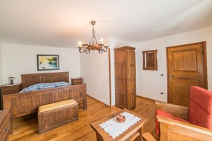 Ein Schlafzimmer aus Holz mit einem Bett, einer Bank, einem Tisch und einem roten Stuhl.