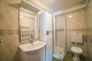 Ein Badezimmer mit Waschbecken, Spiegel, Toilette und Duschkabine.