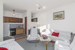 A compact living space with a kitchenette, a sofa, a coffee table, and a painting on the wall.