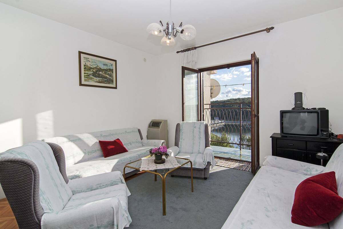 Un salon comprenant un canapé, un fauteuil et une table basse, une télévision, ainsi qu’un balcon avec vue.