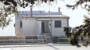 Un edificio pequeño con techo de tejas, una escalera que lleva a una puerta y una barandilla en frente.