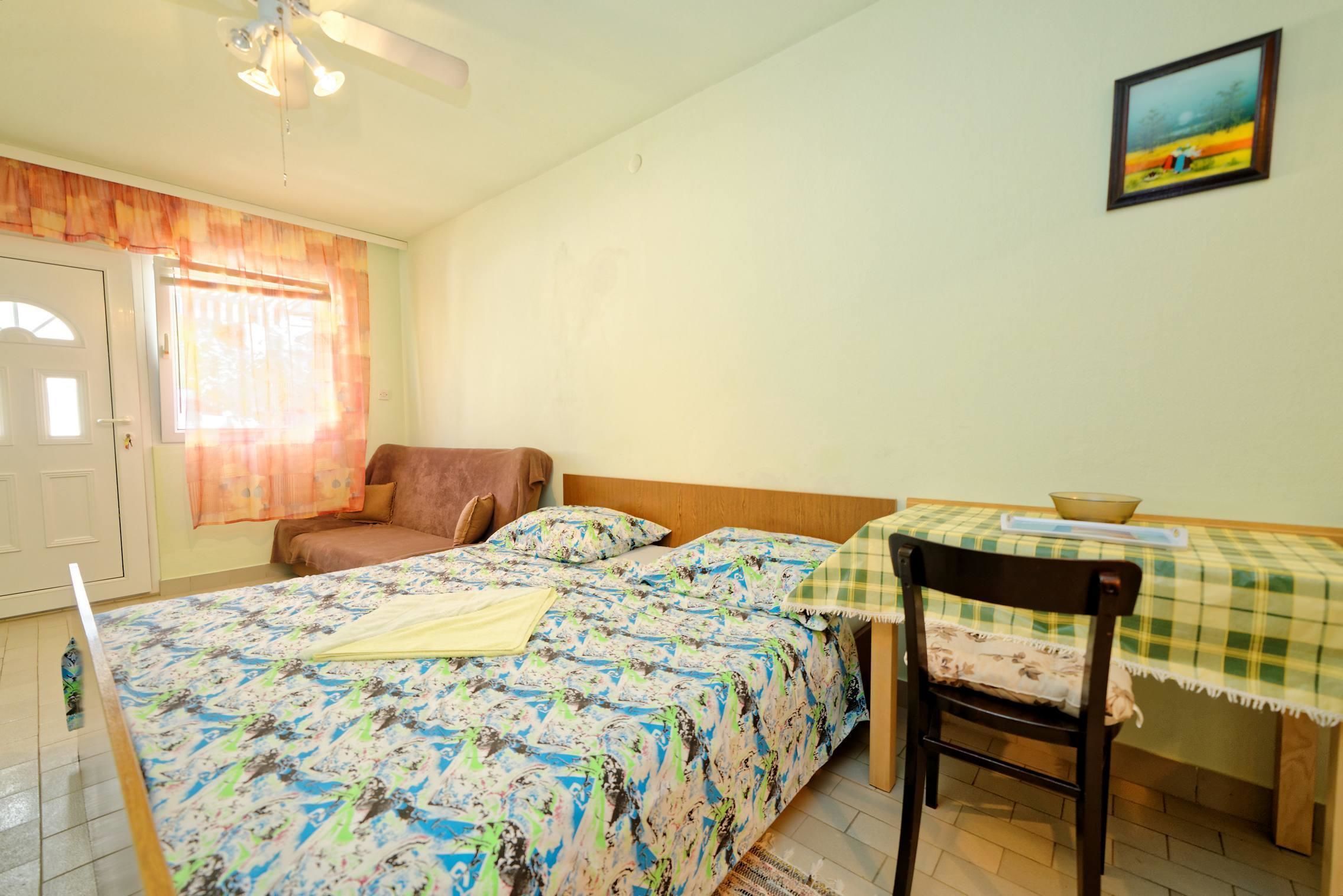 A bedroom with a bed, a chair, a table, and a painting on the wall.
