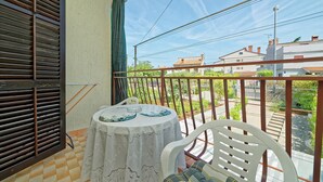 A balcony with a table and chairs, a view of the street, and a building in the background. - App and Rooms Marojevic (Rovinj)