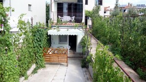 A two-story house with a balcony, a small porch, and a garden area with climbing plants. - App and Rooms Marojevic (Rovinj)