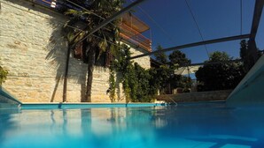 A swimming pool with a stone wall and a wooden deck.