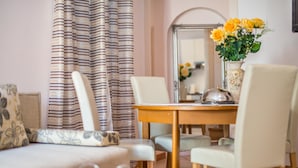 A dining area with a wooden table, white chairs, and a vase of yellow flowers.