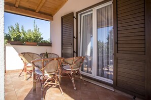 A covered patio with wicker furniture, a table, and a bottle. - Apartments Milan Rovinj (Rovinj)