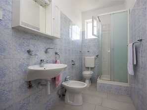 A bathroom with a sink, bidet, toilet, and a glass-enclosed shower.
