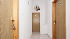 A hallway with wooden doors, a small white refrigerator, and a ship decoration on the wall. - Apartment Vinko (Sibenik)