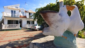 A sculpture of a bird in flight in front of a white building with a balcony and a car parked in front. - Apartment Vinko (Sibenik)