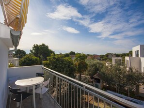 A balcony with a table and chairs, overlooking a residential area with houses and greenery. - Apartment Vinko (Sibenik)