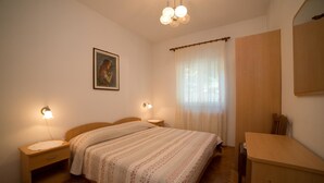 A bedroom with a wooden bed, bedside lamps, a nightstand, a dresser, a mirror, and a painting on the wall. - Apartments Silvano 407 (Porec)