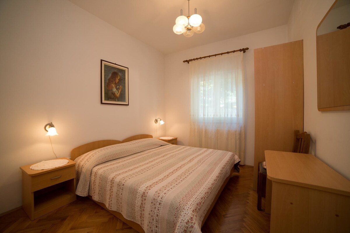 Une chambre à coucher avec un lit en bois, des lampes de chevet, une table de chevet, une commode, un miroir et un tableau accroché au mur.