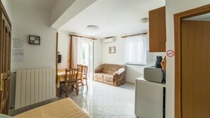 A compact living space with a dining area, a sofa, a kitchenette, and a radiator. - Apartments Silvano 407 (Porec)
