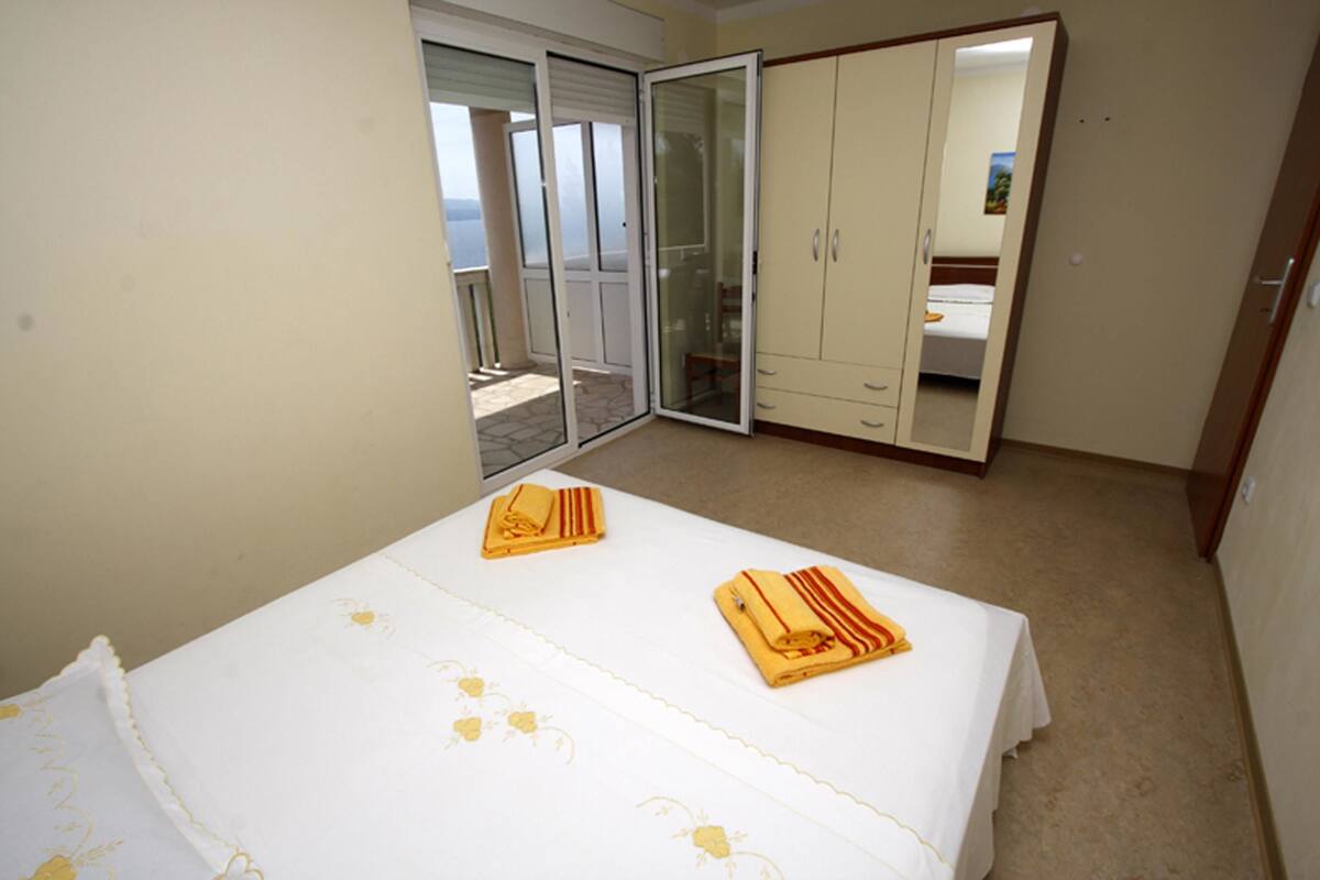 A bedroom with a bed, a wardrobe, and a sliding glass door leading to a balcony.