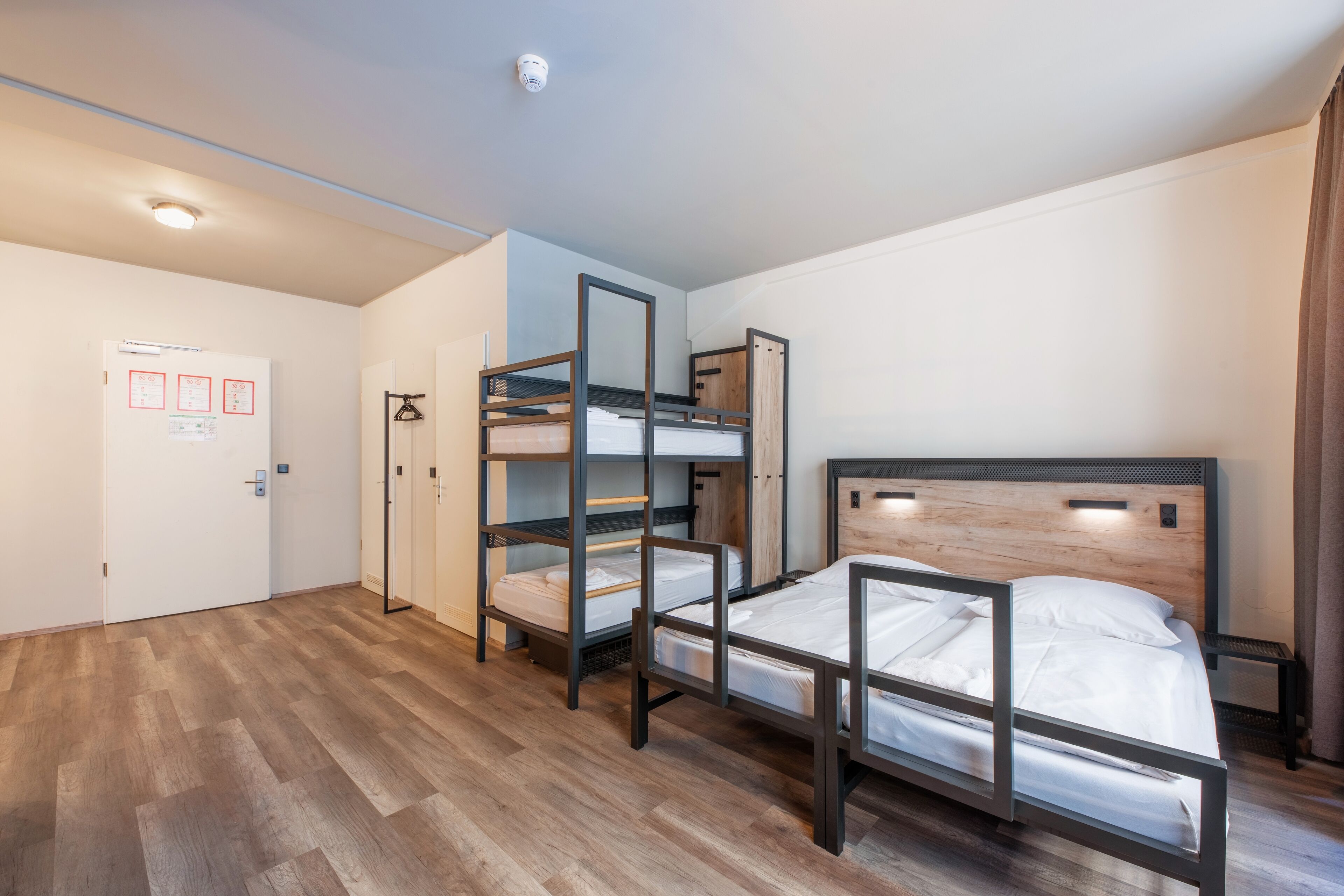 A room with bunk beds, a white door with red markings, and a wooden floor.