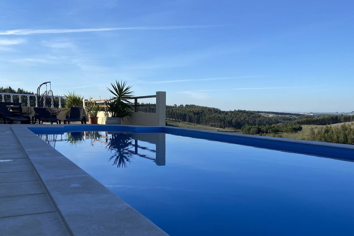 A swimming pool with a clear view of the surrounding landscape, including trees and a distant horizon.