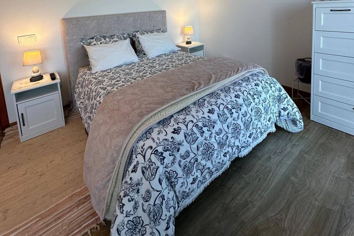 A bedroom with a bed, bedside tables, a dresser, and a ceiling light.
