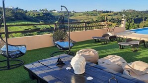 Una terrassa al terrat amb piscina, mobiliari exterior i vistes al camp.