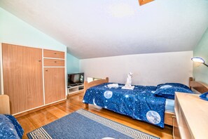 A bedroom with a bed covered in a starry night sky bedspread, a wooden wardrobe, a desk, and a television. - Villa Bubani / Private Pool (Kanfanar)