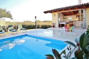 A swimming pool with lounge chairs, a covered outdoor kitchen, and a patio area. - Villa Bubani / Private Pool (Kanfanar)