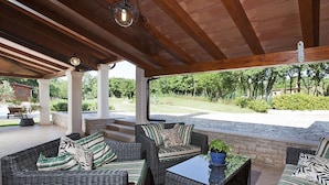 Ein Patio im Freien mit Korbmöbeln und einer Steinmauer.