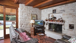 Ein gemütliches Wohnzimmer mit Steinwand, Kamin, Fernseher und bequemen Sitzmöglichkeiten.